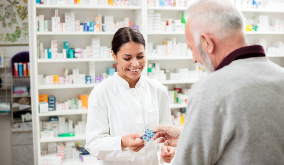 happy pharmacist giving medications to senior man customer