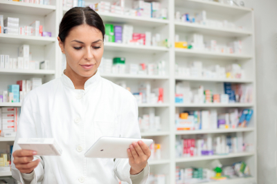 young pharmacist holding a tablet and box of medications.